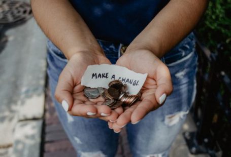 Charity - person showing both hands with make a change note and coins