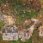 Intestate Consequences - Aerial view of dramatic consequences of massive hurricane with ruined houses and kindling woods lying on green lawn