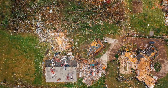Intestate Consequences - Aerial view of dramatic consequences of massive hurricane with ruined houses and kindling woods lying on green lawn